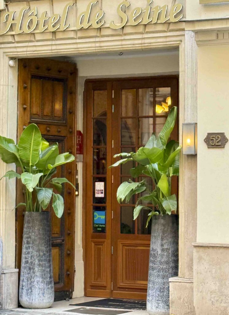 The front door of the Hotel de Seine. Wood and glass with tall exotic plants on each side.